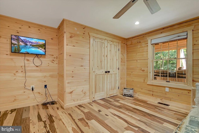 interior space featuring ceiling fan, wooden walls, and light hardwood / wood-style floors