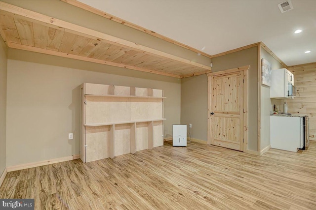 unfurnished living room with beamed ceiling and light wood-type flooring