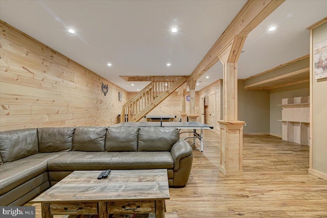 living room featuring wooden walls, decorative columns, and light wood-type flooring