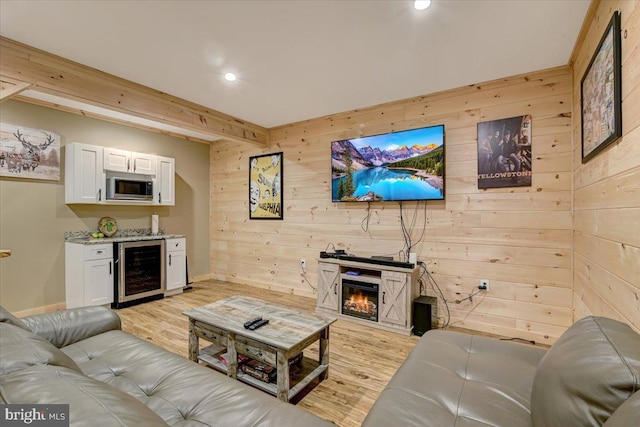 living room with wood walls, light wood-type flooring, and wine cooler