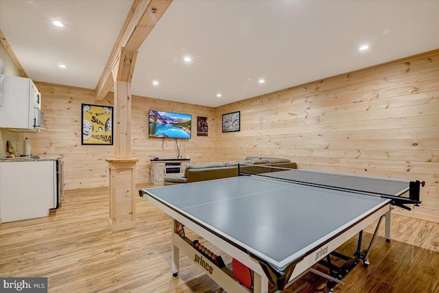 recreation room with light hardwood / wood-style floors and wooden walls