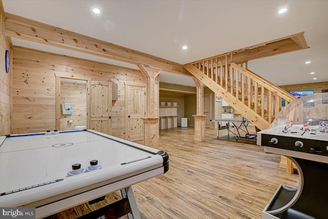 recreation room with light hardwood / wood-style floors and wooden walls