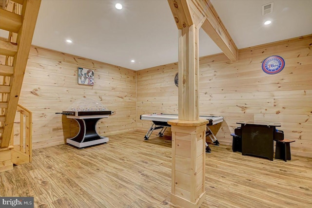 rec room featuring beamed ceiling, wooden walls, and light hardwood / wood-style floors