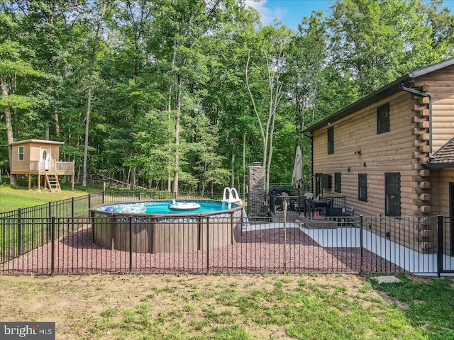 view of pool featuring a deck, a patio, and a lawn