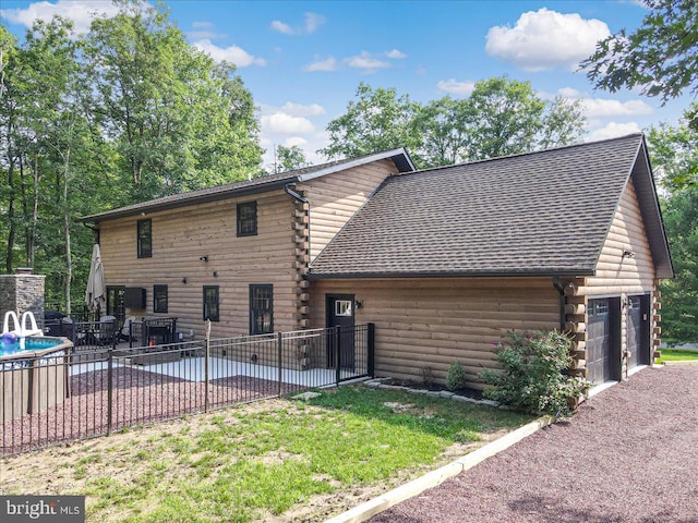 back of property with a garage and a lawn