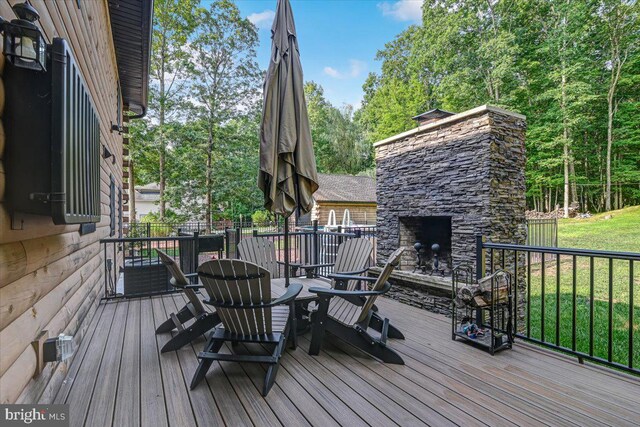 wooden terrace with an outdoor stone fireplace and a yard