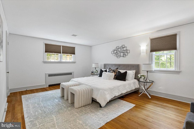 bedroom with radiator and hardwood / wood-style floors