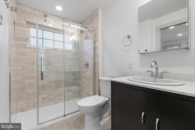 bathroom with vanity, a shower with shower door, and toilet