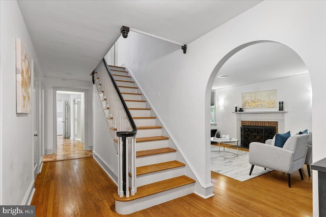 stairs with hardwood / wood-style floors and a fireplace