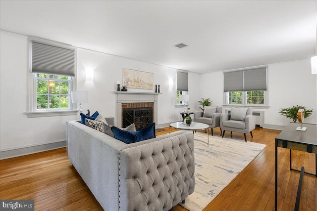 living room featuring a wealth of natural light, radiator, hardwood / wood-style floors, and a fireplace