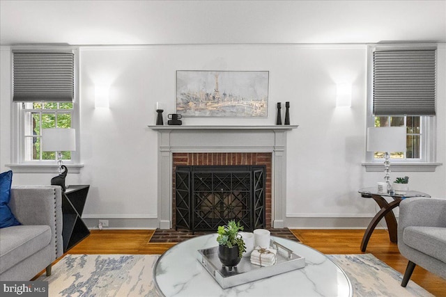 living room with a brick fireplace and hardwood / wood-style floors