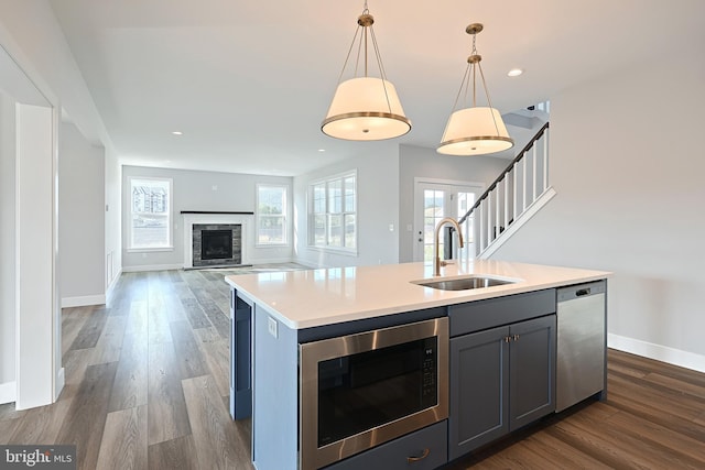 kitchen featuring sink, decorative light fixtures, a center island with sink, gray cabinets, and stainless steel appliances