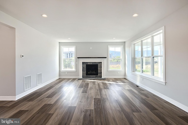 unfurnished living room with dark wood-type flooring, a wealth of natural light, and a fireplace