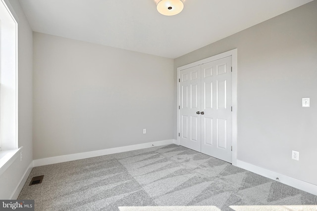 unfurnished bedroom featuring light colored carpet and a closet