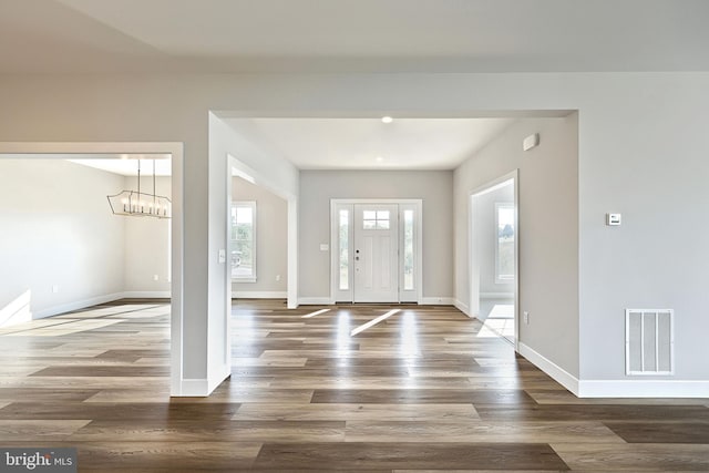 entrance foyer featuring an inviting chandelier and dark hardwood / wood-style floors