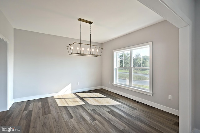 unfurnished dining area featuring dark hardwood / wood-style floors and an inviting chandelier