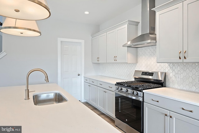 kitchen with sink, decorative backsplash, stainless steel range with gas cooktop, and wall chimney exhaust hood