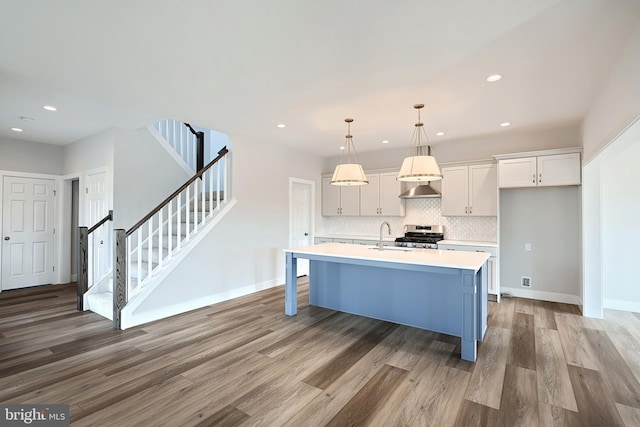 kitchen with wood-type flooring, pendant lighting, a breakfast bar, and a center island with sink