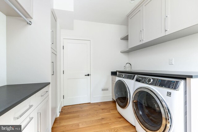 607 W Gravers Ln, Philadelphia, PA 19118 - laundry room featuring separate washer and dryer, light wood-style floors, and cabinet space