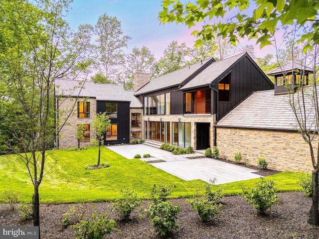 607 W Gravers Ln, Philadelphia, PA 19118 - rear view of house featuring stone siding, a chimney, a balcony, a lawn, and a patio