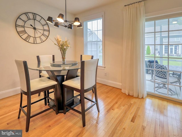 dining area with light hardwood / wood-style floors and a chandelier