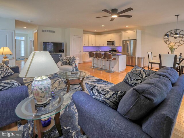 living room with light wood-type flooring and ceiling fan