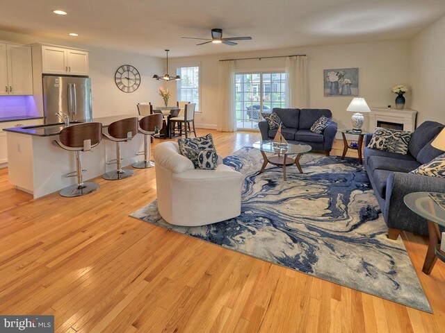 living room featuring light hardwood / wood-style floors, sink, and ceiling fan