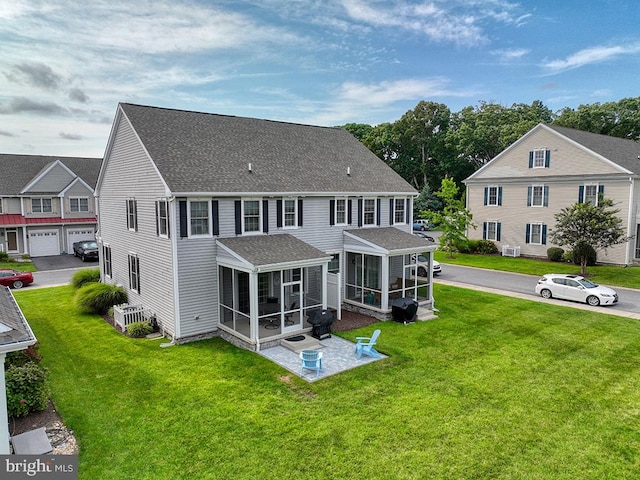 back of house with a lawn, a garage, and a sunroom