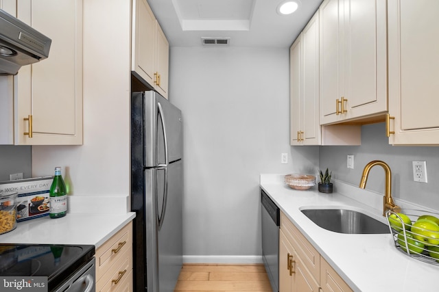 kitchen with light wood finished floors, stainless steel appliances, visible vents, a sink, and under cabinet range hood