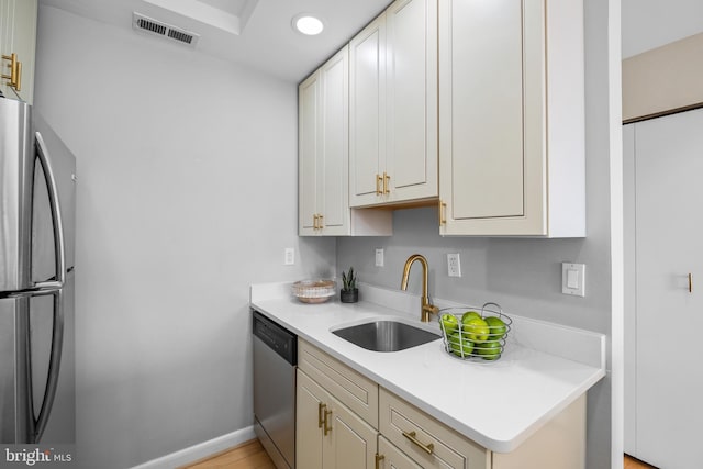 kitchen featuring a sink, visible vents, baseboards, light countertops, and appliances with stainless steel finishes