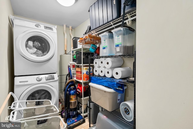 laundry room featuring stacked washer and dryer and tile patterned floors