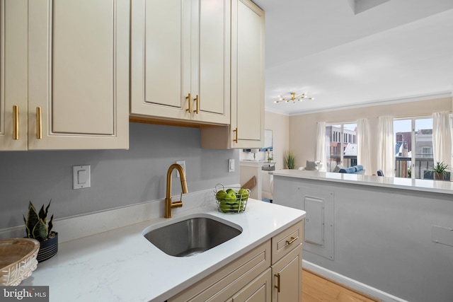 kitchen featuring crown molding, open floor plan, light countertops, and a sink