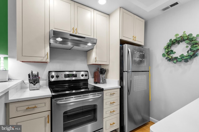 kitchen with stainless steel appliances, light hardwood / wood-style floors, and cream cabinetry