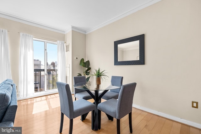 dining room with ornamental molding, light wood-type flooring, and baseboards