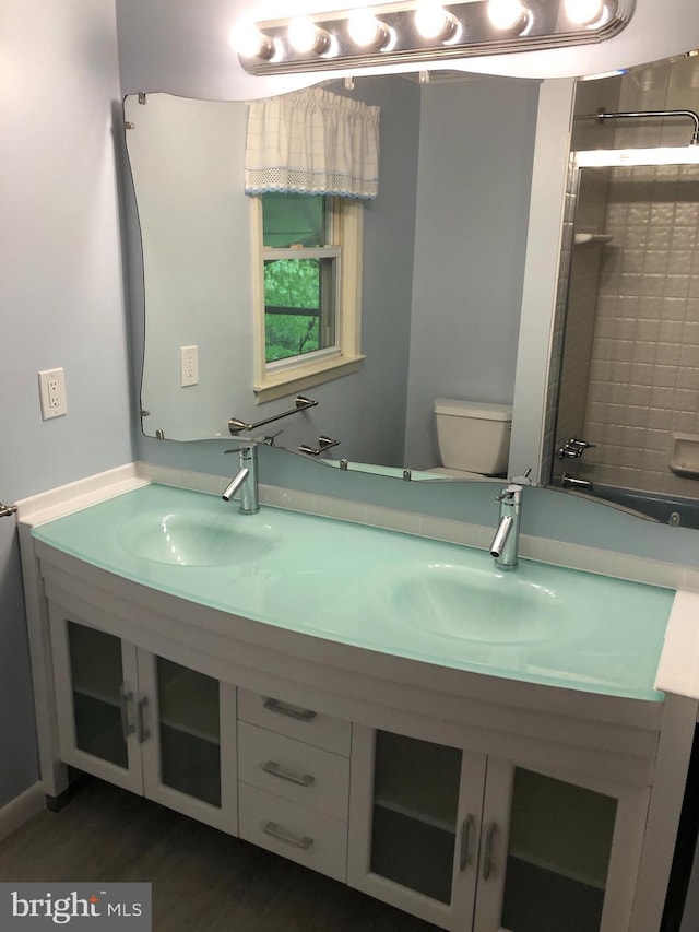 bathroom featuring hardwood / wood-style flooring, vanity, a shower, and toilet