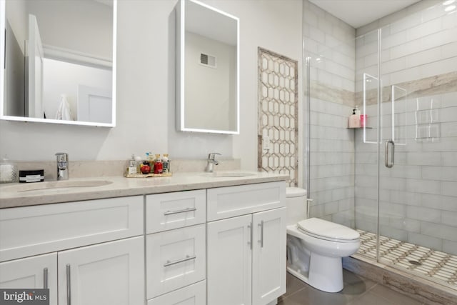 bathroom with tile patterned floors, a shower with shower door, toilet, and vanity