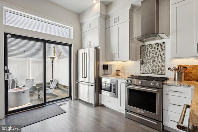 kitchen featuring wall chimney range hood, white cabinets, stainless steel appliances, and dark hardwood / wood-style flooring