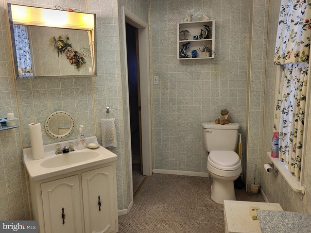 bathroom with vanity, toilet, and tile walls