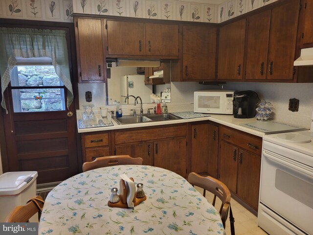 kitchen with light tile patterned floors, white appliances, and sink