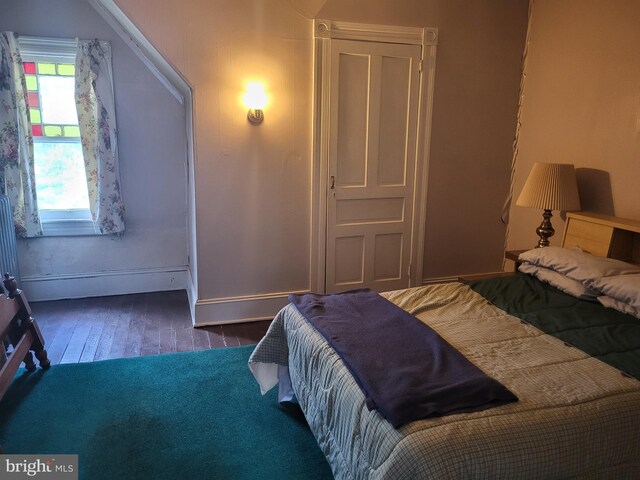 bedroom with dark wood-type flooring and a baseboard radiator