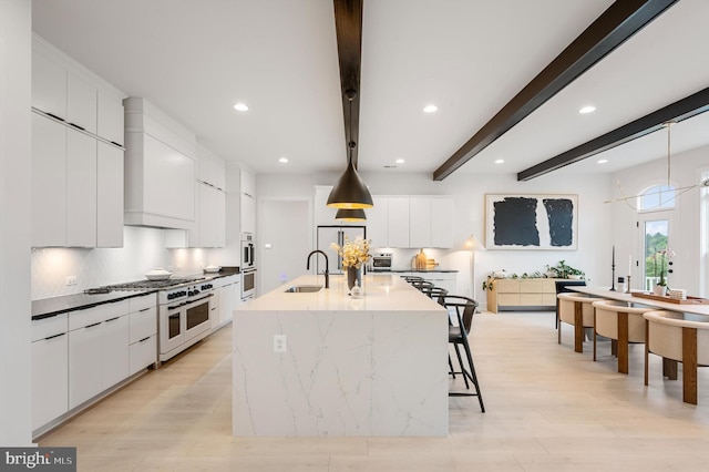 kitchen featuring a large island, sink, and white cabinets