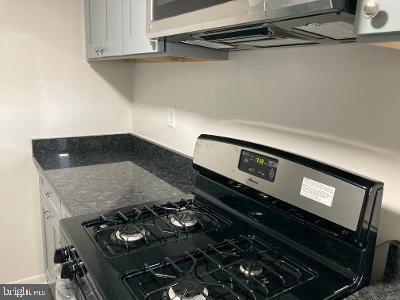 kitchen with dark stone countertops, gas range oven, and white cabinets