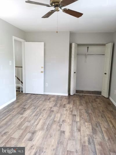 unfurnished bedroom with hardwood / wood-style floors, ceiling fan, and a closet