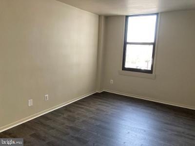 unfurnished room with dark wood-type flooring