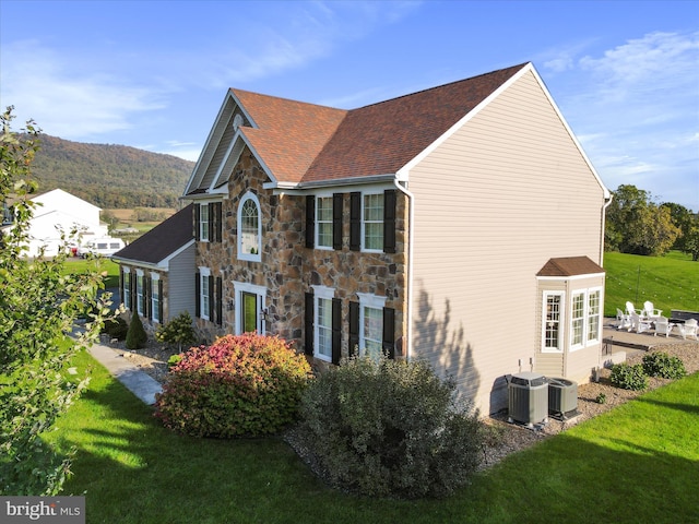 view of property exterior with cooling unit, a mountain view, and a lawn