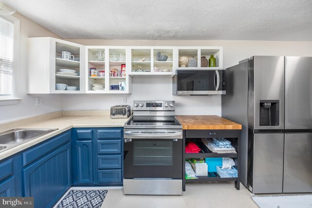 kitchen featuring sink, appliances with stainless steel finishes, blue cabinetry, and a textured ceiling