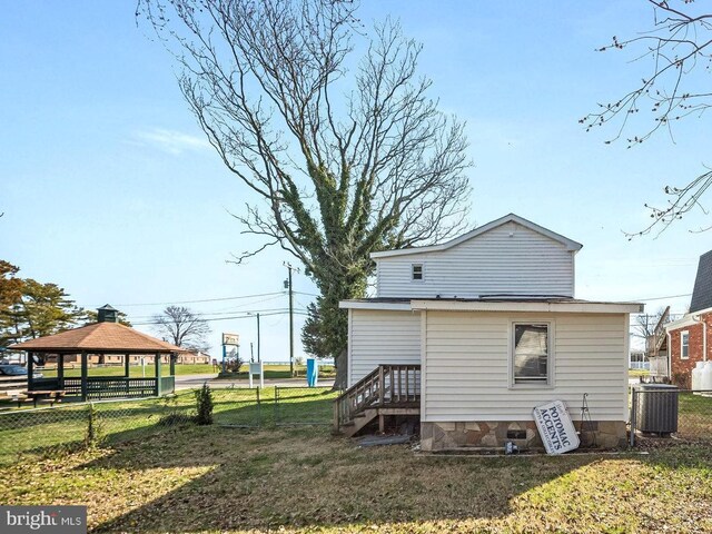 rear view of property featuring central air condition unit, a lawn, and a gazebo