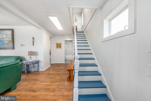 stairway featuring wood-type flooring and a textured ceiling