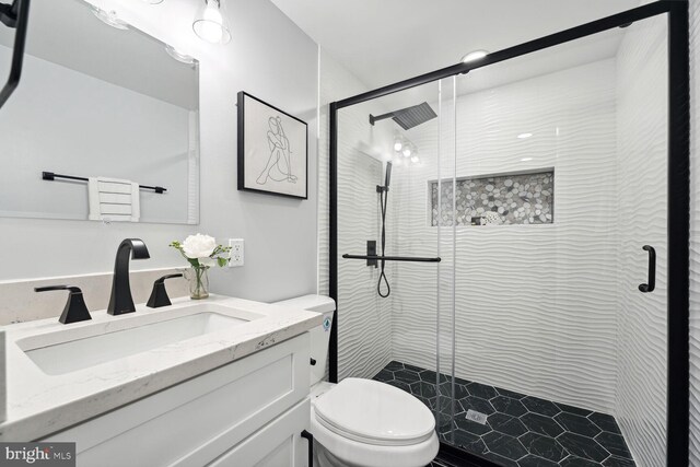 bathroom with vanity, a shower with shower door, and toilet