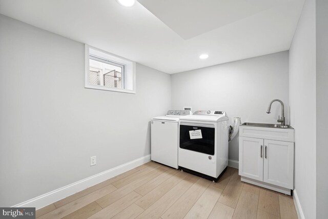 washroom featuring cabinets, separate washer and dryer, sink, and light hardwood / wood-style floors